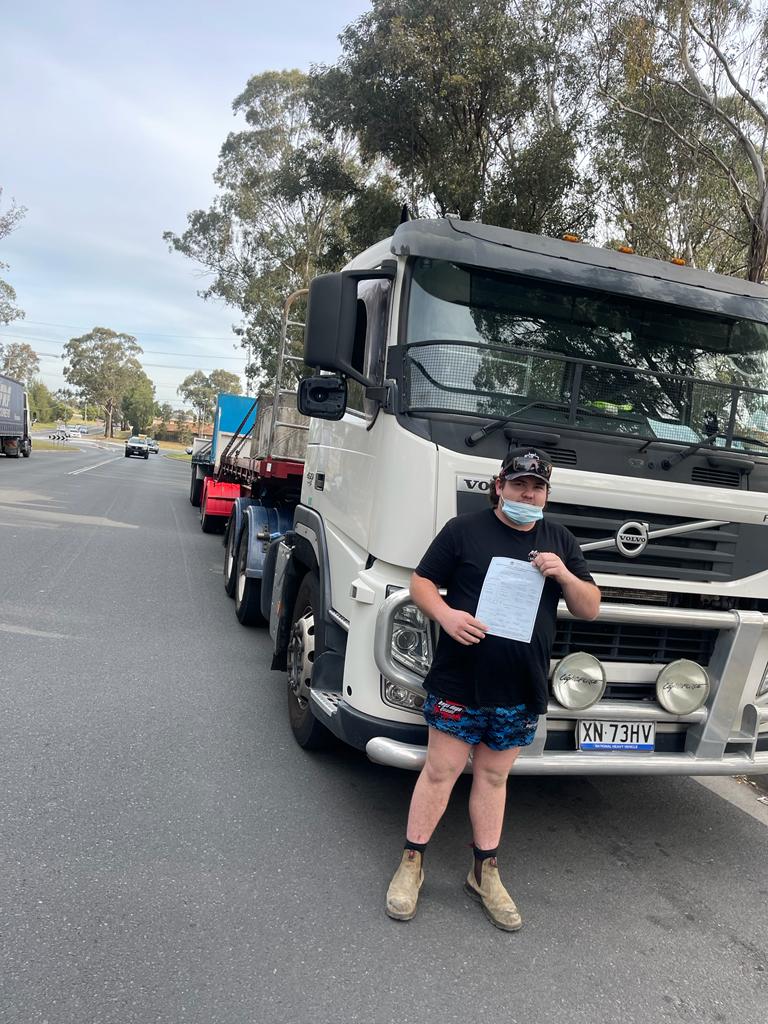 young man posing with his truck driving certificate