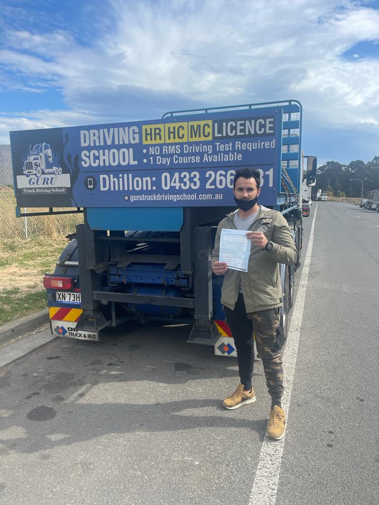 Brown skinned man posing with his truck driving certificate